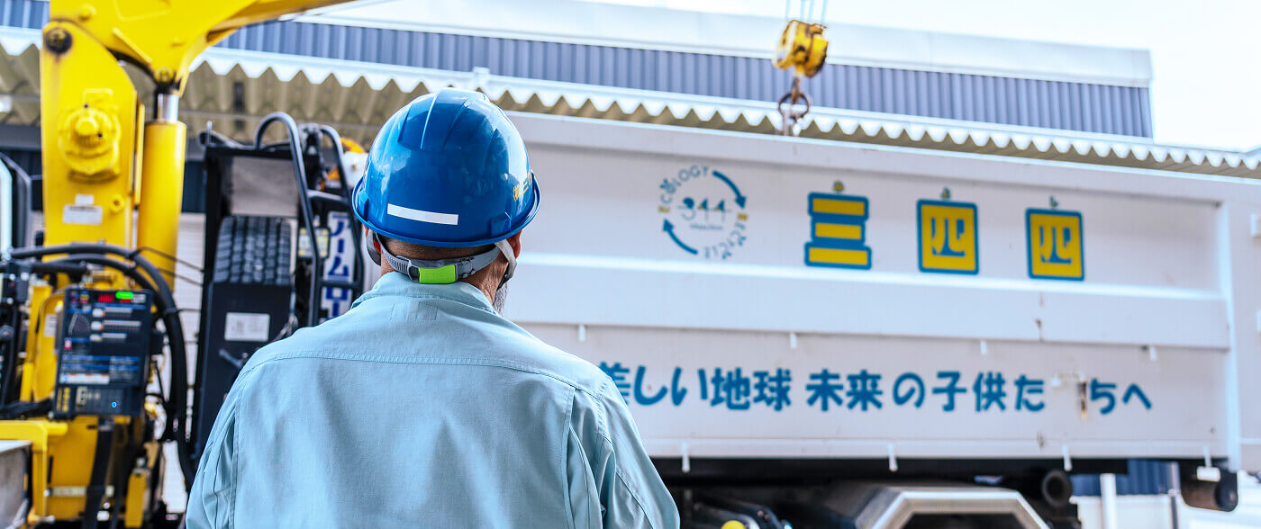 働く社員の後ろ姿と運搬車の写真